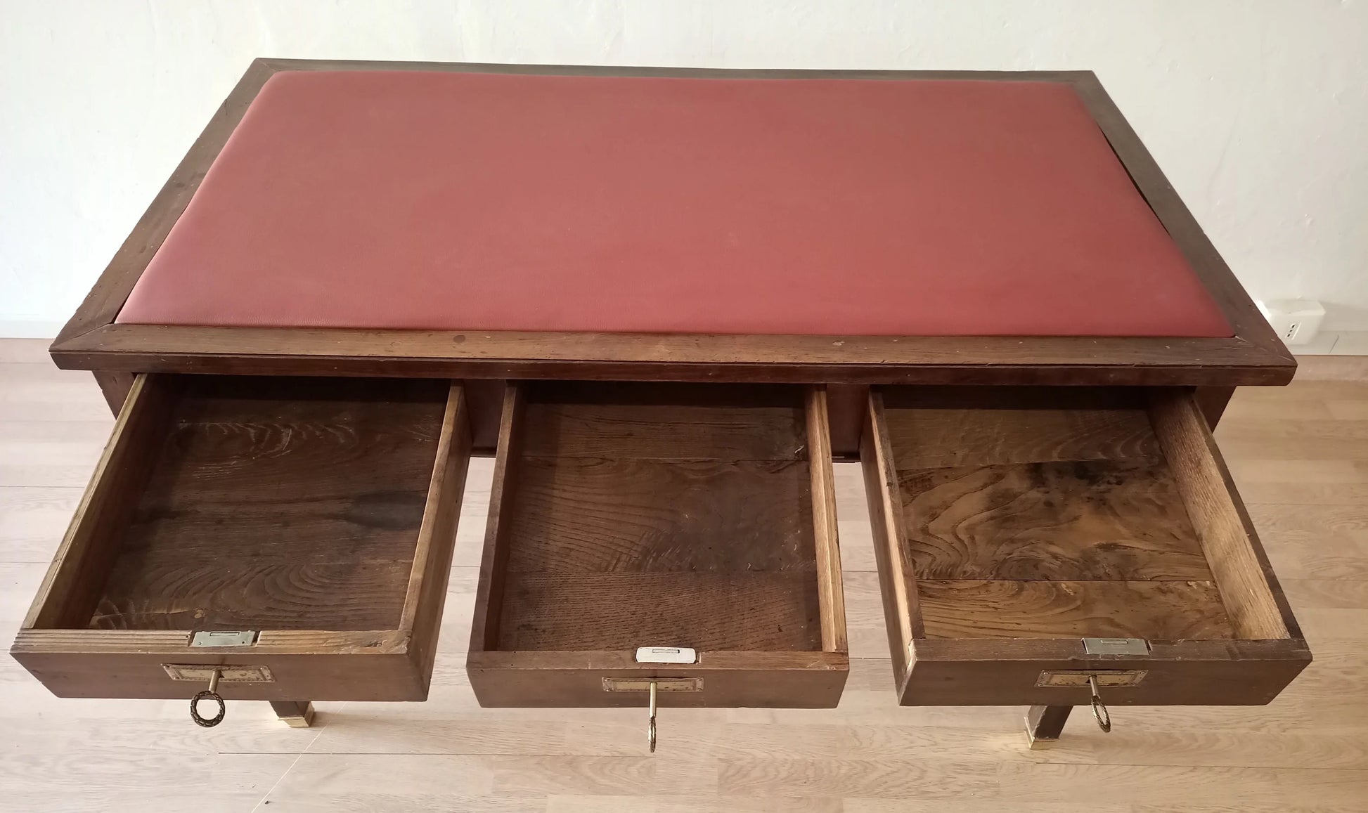Scrivania stile impero in noce con piano in pelle rossa e tre cassetti aperti con piedini in ottone