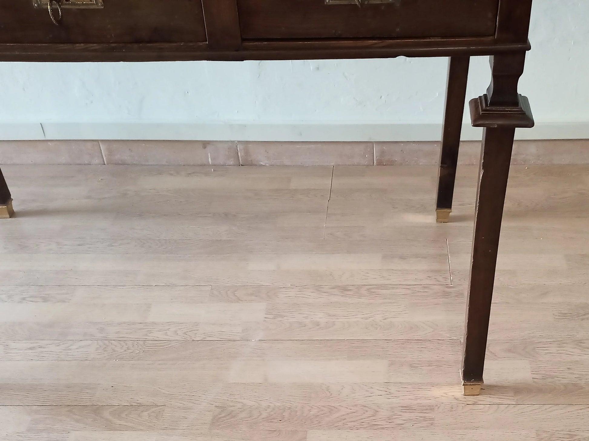 Gambe in legno noce stile impero con piedini in ottone su pavimento in legno della scrivania vintage stile impero